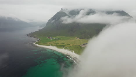 Descending-aerial-footage-of-Vik-Beach-and-Hauklandstranda-Norway,-coastline-drone-shot-with-turquoise-blue-water-moving-through-clouds