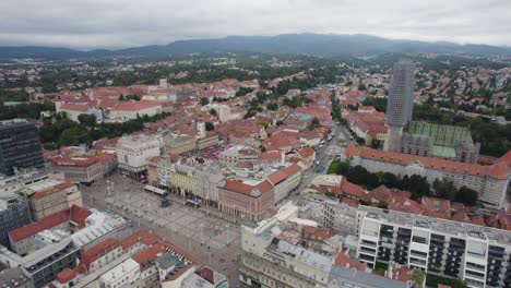 Establishing-aerial-view-rising-back-from-Zagreb,-Croatian-old-town-red-tiled-rooftops-and-urban-skyline