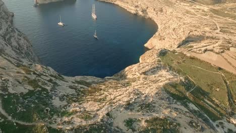 Aerial-drone-footage-of-Dwejra-Bay,-heading-to-Fungus-Rock,-passing-luxurious-yachts,-then-soaring-above-the-majestic-formation,-revealing-the-vast-sea