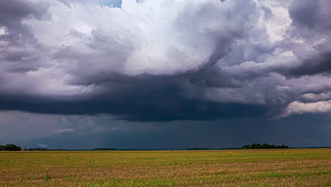 Dark-storm-clouds-above-rural-landscape,-time-lapse-view