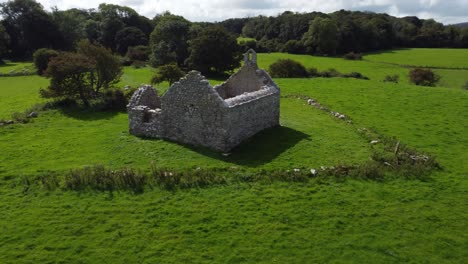 Aerial-view-establishing-reveal-Capel-Lligwy-ruined-chapel-on-Anglesey-island-coastline,-North-Wales