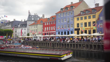 Tourist-boat-glides-through-Nyhavn,-offering-stunning-views-of-colorful-canal-side-houses