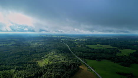 Rain-clouds-flowing-above-forestry-flatlands,-aerial-view