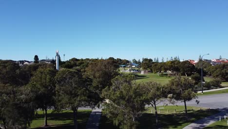 Aerial-Reveal-Shot-Of-Modern-Lighthouse-Glowing-In-Park,-Mindarie---Perth