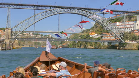 Los-Turistas-Durante-El-Recorrido-En-Barco-Por-El-Río-Duero-Cruzando-El-Famoso-Puente-Dom-Luís-I-En-Porto,-Portugal