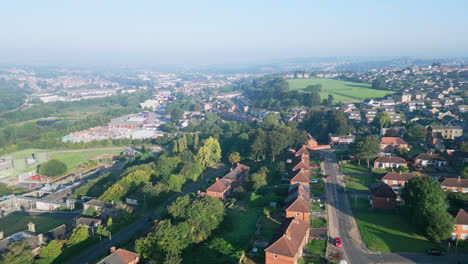 Dewsbury-Moore-Council-estate,-UK,-is-captured-by-a-drone,-highlighting-red-brick-homes-and-the-industrial-Yorkshire-scenery-on-a-sunny-summer-morning