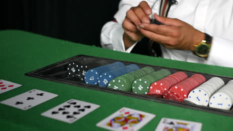 A-poker-dealer-croupier-in-a-casino-counting-and-paying-out-chips-to-a-winner-at-a-black-jack-cards-table