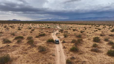 Vehículo-Utilitario-Deportivo-Conduciendo-Por-Una-Carretera-Del-Desierto-De-Mojave---Seguimiento-Aéreo