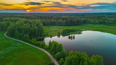 Glassy-pond-and-forest-during-a-golden-sunset---aerial-hyper-lapse