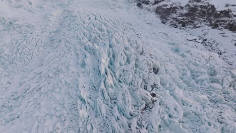 Aerial-view-over-irregular-ice-formations-in-Falljokull-glacier-covered-in-snow,-Iceland