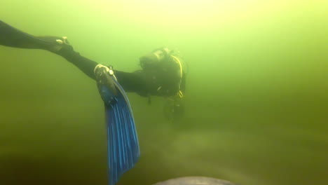 Slow-motion-of-a-scuba-diver-in-a-murky-lake-with-a-seascooter