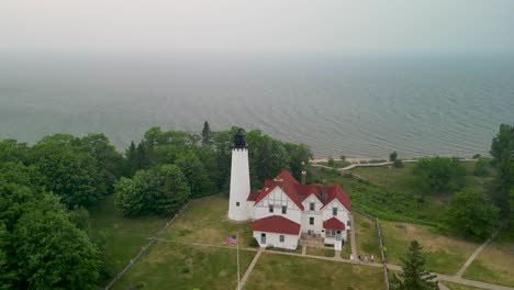 Aerial-orbit-of-Point-Iriquois-Lighthouse-with-wildfire-smoke,-Lake-Superior,-Michigan