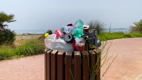 Overfilled-trash-dumpster-by-the-beach,-people-not-recycling-garbage,-plastic-and-bottles-in-Marbella-Spain,-4K-shot