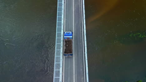 Truck-crossing-a-bridge-over-a-river---straight-down-aerial-view