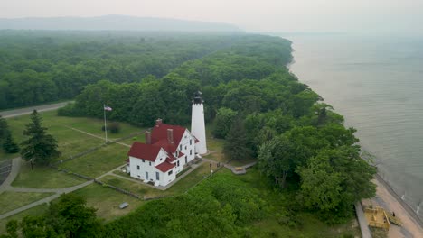 Aerial-view-of-Point-Iriquoise-Lighthouse-and-shoreline,-Lake-Superior,-Michigan-during-Canadian-wildfire-smoke