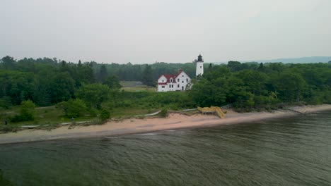Aerial-view-of-Point-Iriquois-Lighthouse-and-beach-with-wildfire-smoke,-Lake-Superior,-Michigan