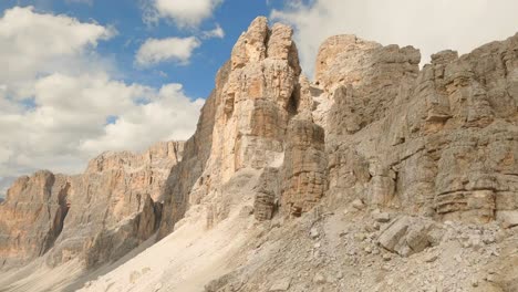 Drone-ascends-Lagazuoi-mountain,-Italian-Dolomites,-piercing-through-clouds-veiling-the-rocky-ridge