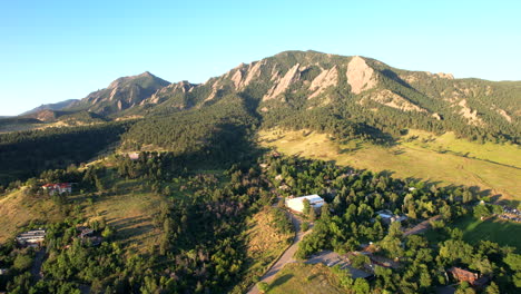 Drone-Dando-Marcha-Atrás-Sobre-Un-Vecindario-En-Boulder,-Colorado,-Estados-Unidos,-En-Una-Mañana-De-Verano-Con-Las-Montañas-De-Hierro-Plano-Y-El-Parque-Chautauqua-Al-Fondo