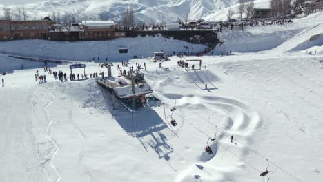 Aerial-view-lift-of-Farellones-snow-resort-packed-with-tourists,-mountains-in-Background