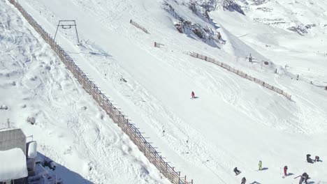 Sobrevuelo-De-Drones-Por-Una-Pendiente-Nevada-Con-Esquiadores-Y-Practicantes-De-Snowboard-En-La-Estación-De-Esquí-De-Farellones,-Chile