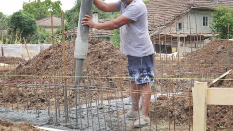 Man-pours-concrete-into-house-foundation-reinforced-rebar-trench