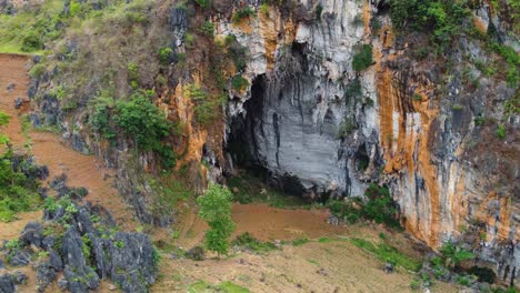 Exterior-wall-and-entrance-to-limestone-cave-somewhere-in-Vietnam,-Aerial,-parallax