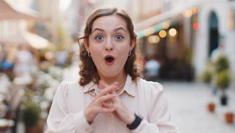 Young-woman-looking-surprised-at-camera-shocked-by-sudden-win-good-victory-news,-wow-in-city-street