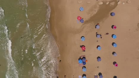 Sommertag-An-Einem-örtlichen-Strand-Mit-Leuten,-Die-Sich-Unter-Sonnenschirmen-Entspannen-Und-Wellen-Brechen