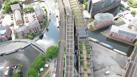 Aerial-drone-flight-over-the-rooftops-of-Castlefield-Quays-in-Manchester-City-Centre-with-a-view-of-a-moving-tram-below