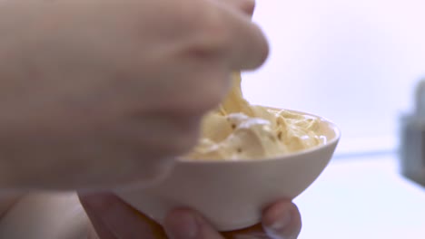 Hand-stirring-bowl-of-salted-caramel-gelato-with-yellow-spoon,-closeup