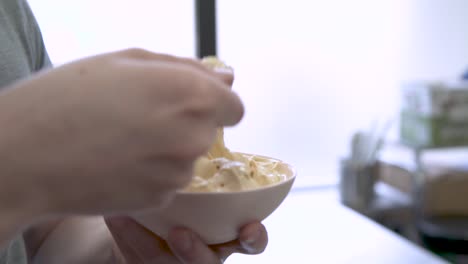 Hand-stirring-and-scooping-cup-of-gelato-with-yellow-spoon
