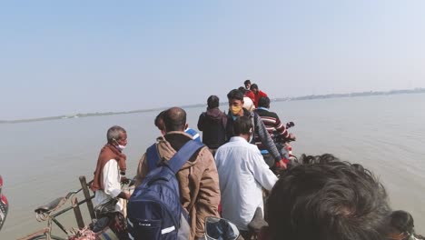 People-standing-on-a-traditional-ferry-boat-crossing-river-at-Sunderban-islands-in-24-Parganas-West-Benagal-India