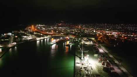 Aerial-night-illuminated-cityscape-of-Timaru-town-over-harbour,-South-Island,-New-Zealand