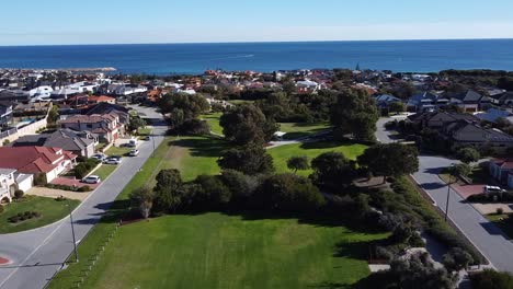 Aerial-Flyover-Park-With-Ocean-And-Marina-In-Background,-Mindarie-Perth---Australia