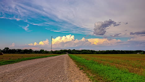 Gravel-road,-green-fields-and-vibrant-cloudscape-time-lapse