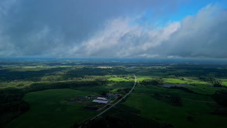 Stormy-clouds-flowing-above-flatlands-of-Latvia,-aerial-view