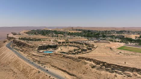 Ramon-crater-edge-and-town-of-Mitzpe-Ramon-in-the-horizon,-Aerial-view