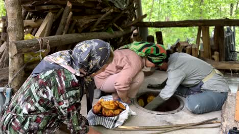 Bake-fresh-hot-delicious-bread-in-the-clay-old-traditional-oven-in-forest-rural-village-with-family-women-life-freedom-concept-of-local-nomad-life-summer-season-spring-green-fresh-air-wood-fire-camp