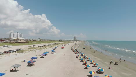 Aerial-view-of-colorful-beach-umbrellas-under-blue-skies-with-white-clouds-at-Porretto-beach-on-Galveston-Island-Texas