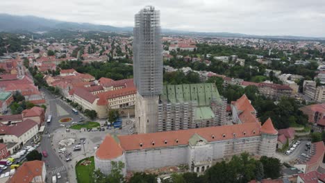 Aerial-view-circling-the-Cathedral-of-Zagreb-with-scaffolding-restoration-on-the-upper-tower-overlooking-Croatian-cityscape