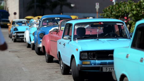 Fila-De-Viejos-Autos-Retro-Al-Costado-De-La-Calle-En-La-Habana,-Cuba-Con-Una-Persona-Caminando-Hacia-Ellos