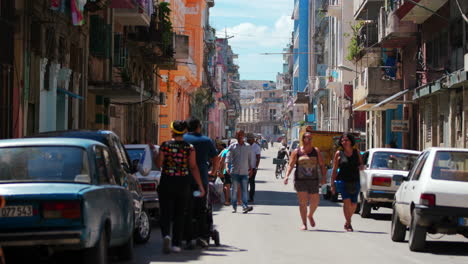 Locals-Walking-Along-Middle-Of-Road-In-Typical-Cuban-Street-On-Sunny-Day