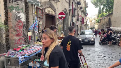Scene-of-tourists-exploring,-workers-working,-and-vendors-selling-souvenirs-in-Spaccanapoli,-the-most-famous-straight,-narrow-and-packed-with-charm-street-in-Naples,-Italy