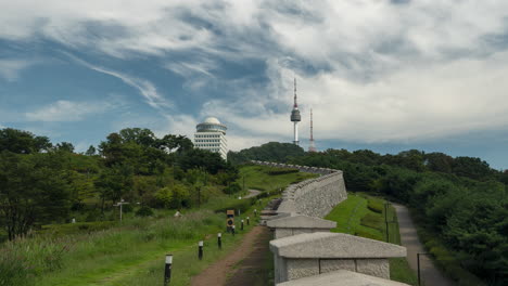 Seoul-City-Wall-and-Namsan-Tower,-Timelapse-of-Tourists-Walking-by-Sightseeing-Ancient-Korean-Fortification-on-Summer-Day---Zoom-in