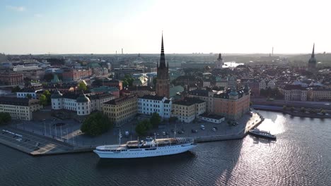 Riddarholmen-Church-tower,-drone-reveal-of-scenic-cityscape-full-of-historic-buildings-in-Stockholm