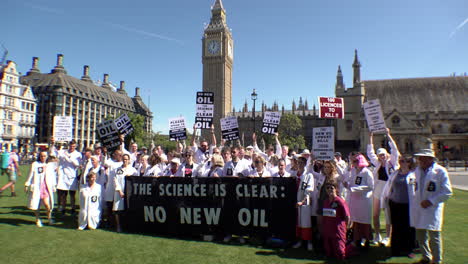 A-group-of-scientists-stand-on-Parliament-Square-in-front-of-Big-Ben-and-hold-a-banner-that-reads,-“The-science-is-clear,-no-new-oil”-on-a-protest-calling-for-no-new-exploration-or-licences