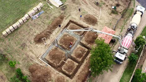 Ready-mix-concrete-pours-into-excavated-trench-building-site-drone-view