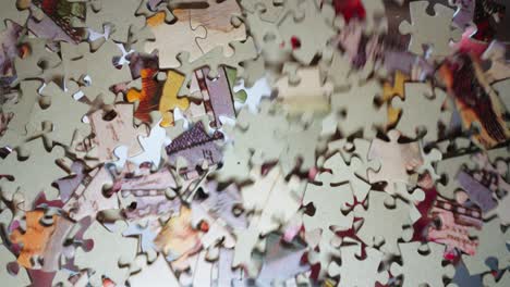 Puzzle-pieces-scattered-on-the-glass-and-a-hand-looking-for-the-right-piece