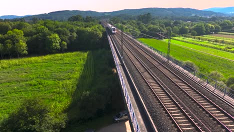 Railroad-With-Train-Traveling-On-Tracks-Over-Green-Rural-Landscape-In-Padrón,-Rois-A-Coruña,-Spain