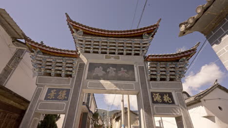 Caminando-A-Través-De-La-Tradicional-Puerta-De-Arco-Paifang-Chino-En-Un-Pequeño-Pueblo-En-Yunnan,-China
